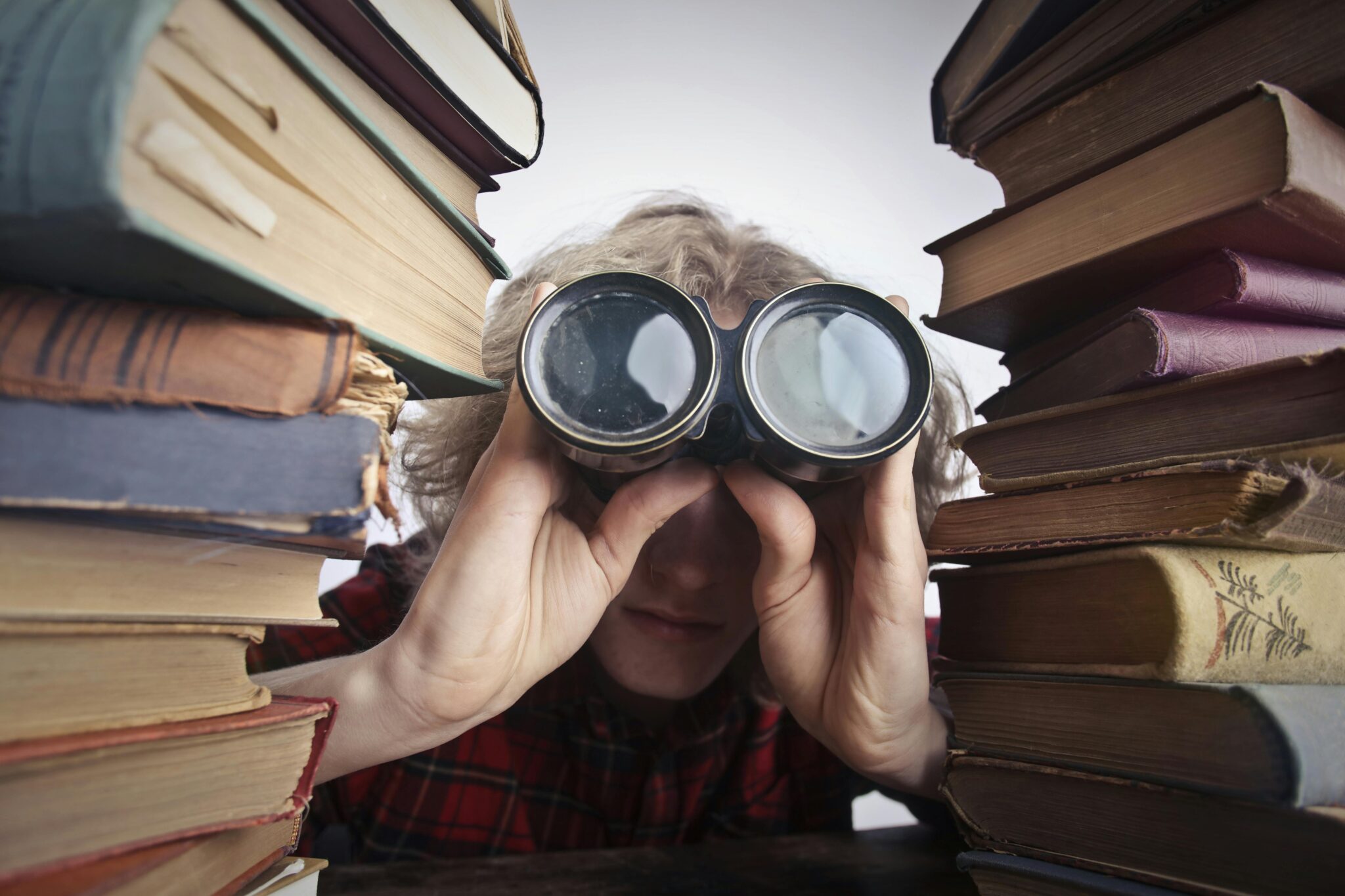 Higher education market research: The Ultimate Guide (woman looks through binoculars, surrounded by books)